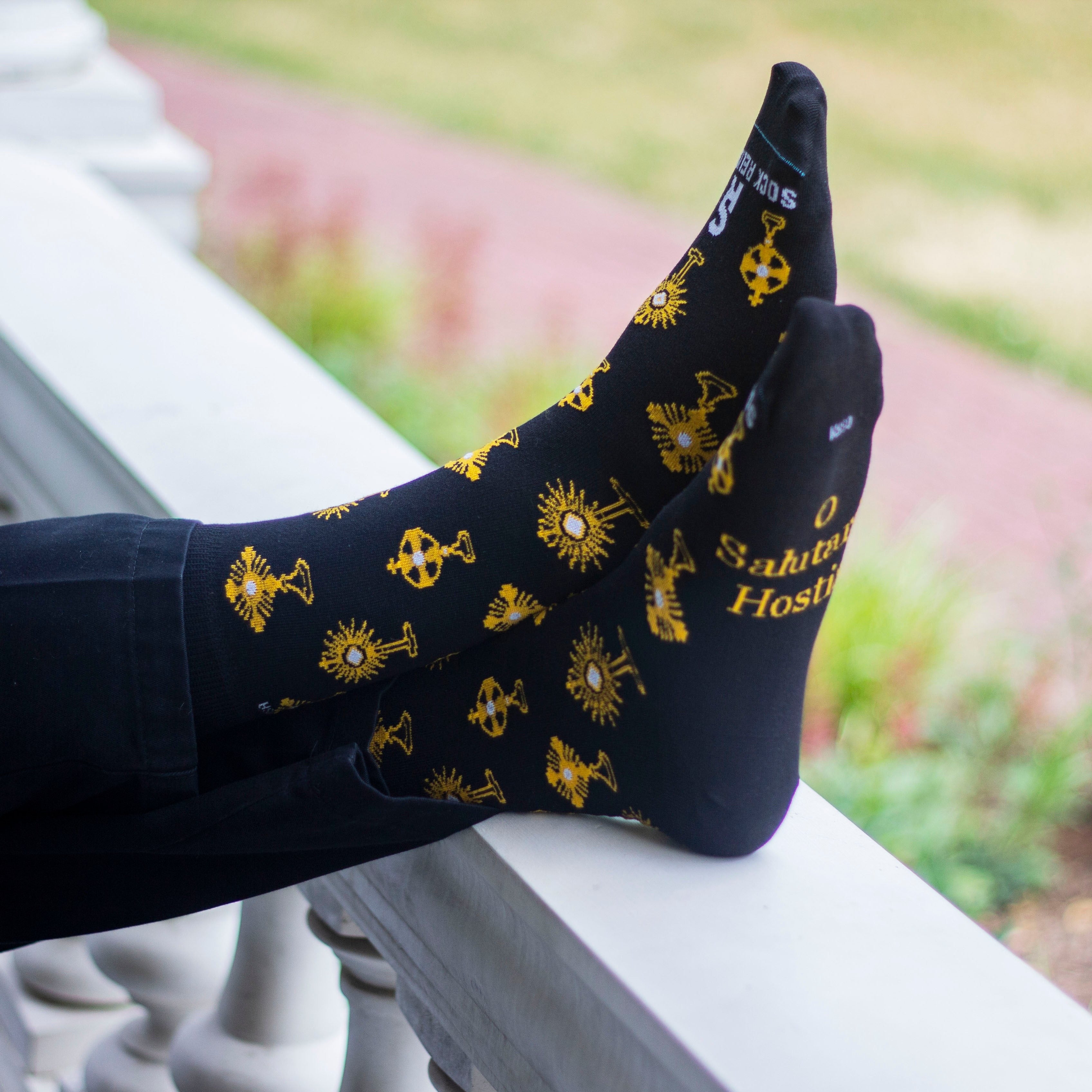 Feet in black socks with gold monstrances and text