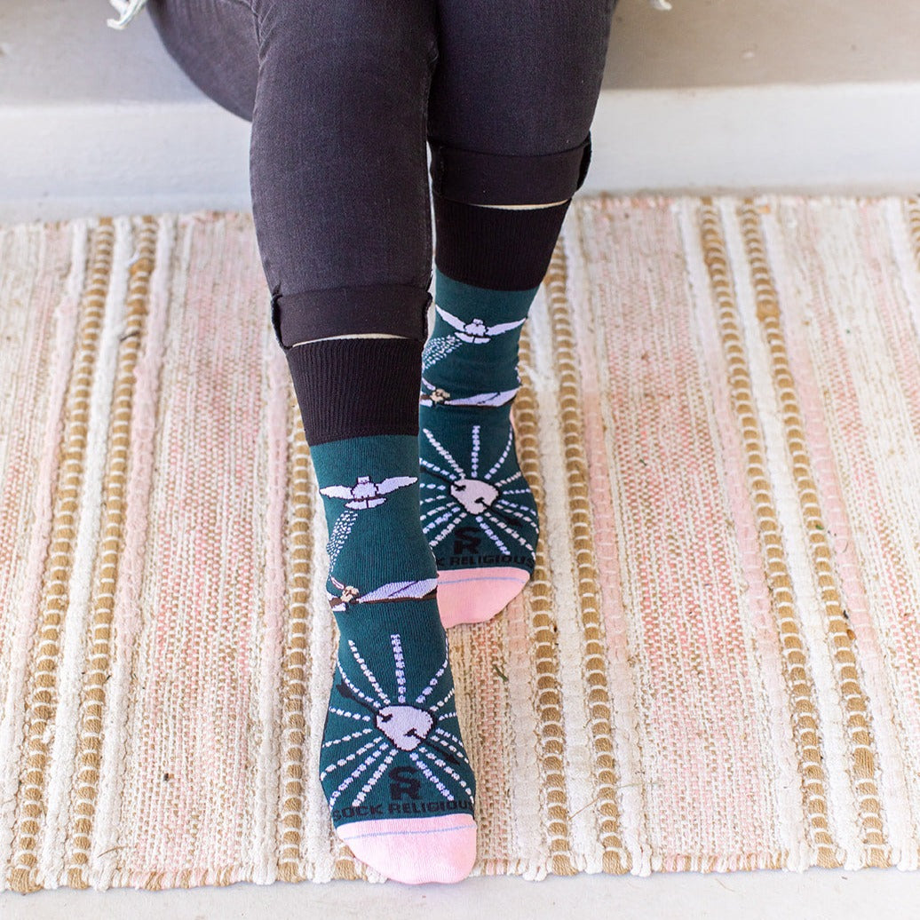 a woman wearing a pair of St. Teresa of Avila socks sitting on top of a rug