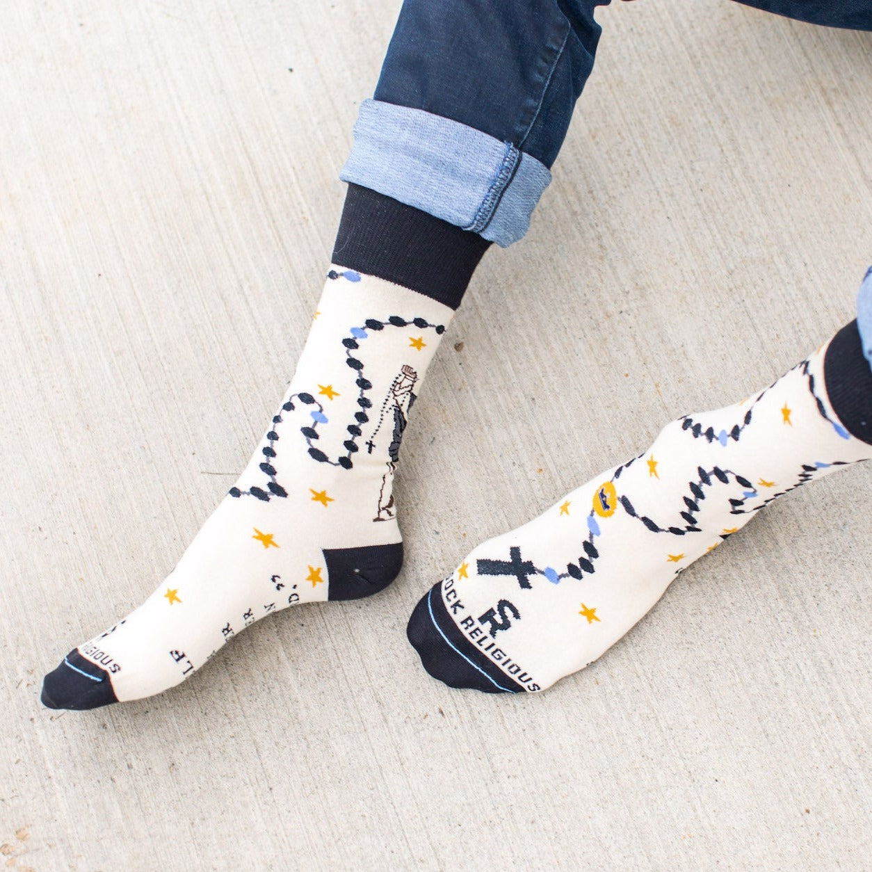 a person sitting on the ground with their feet up wearing a pair of socks with a picture St. Dominic on it