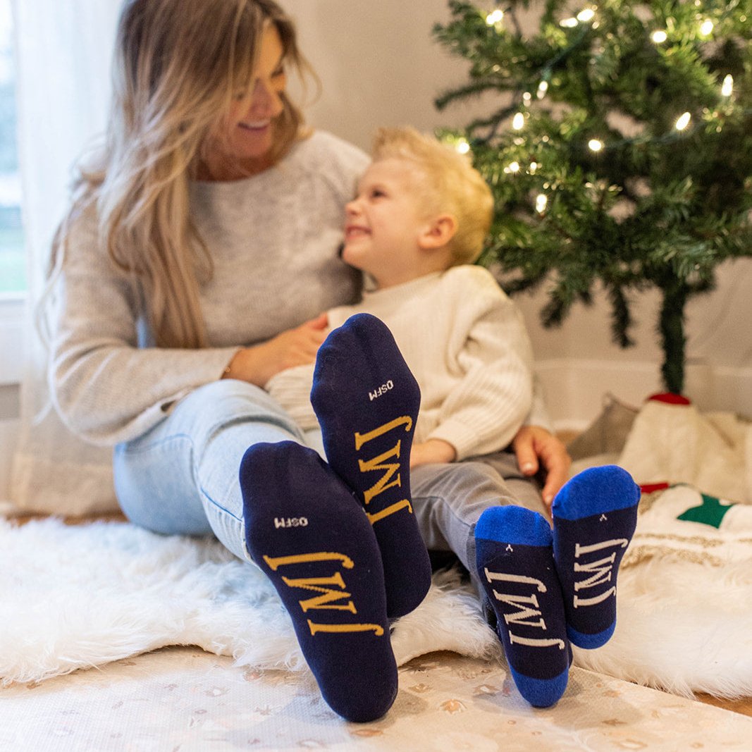 a woman and a child sitting on the floor near a christmas tree