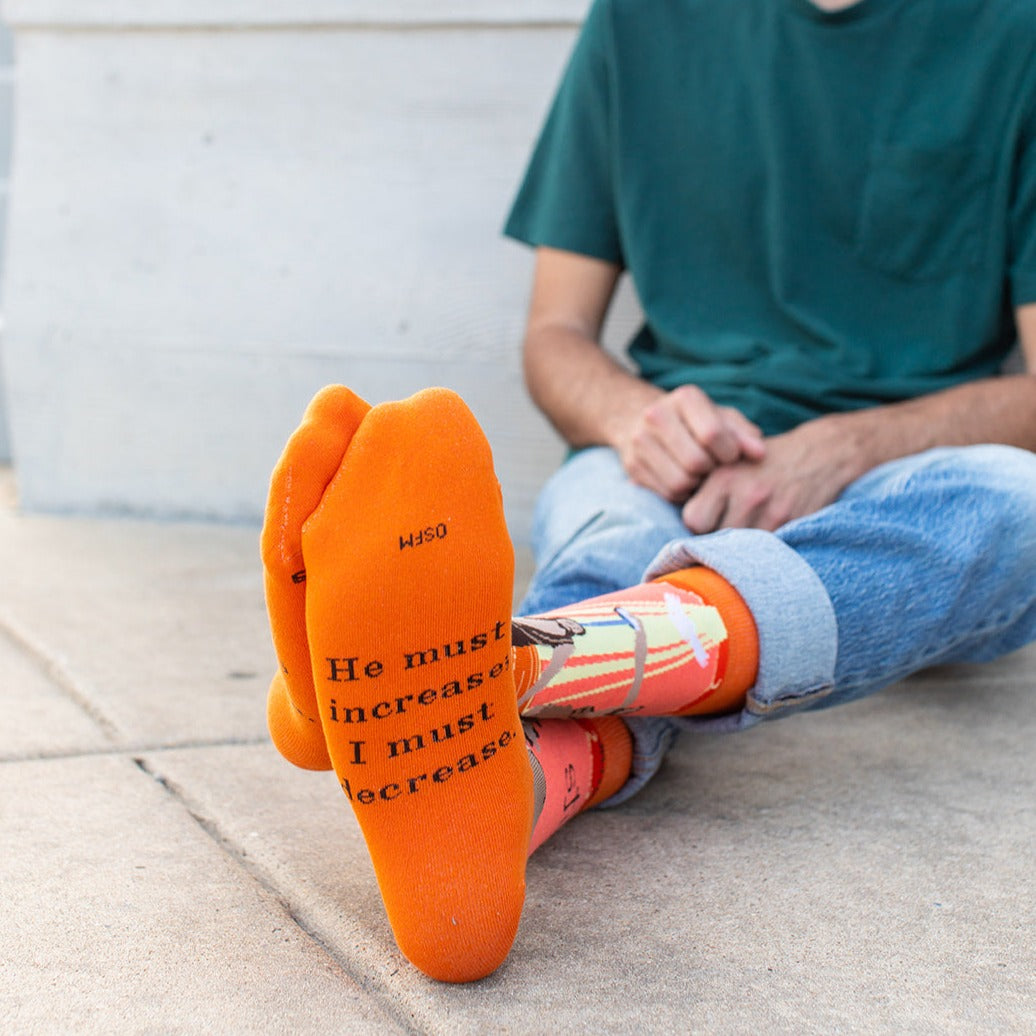 a man sitting on the ground next to a pair of orange socks