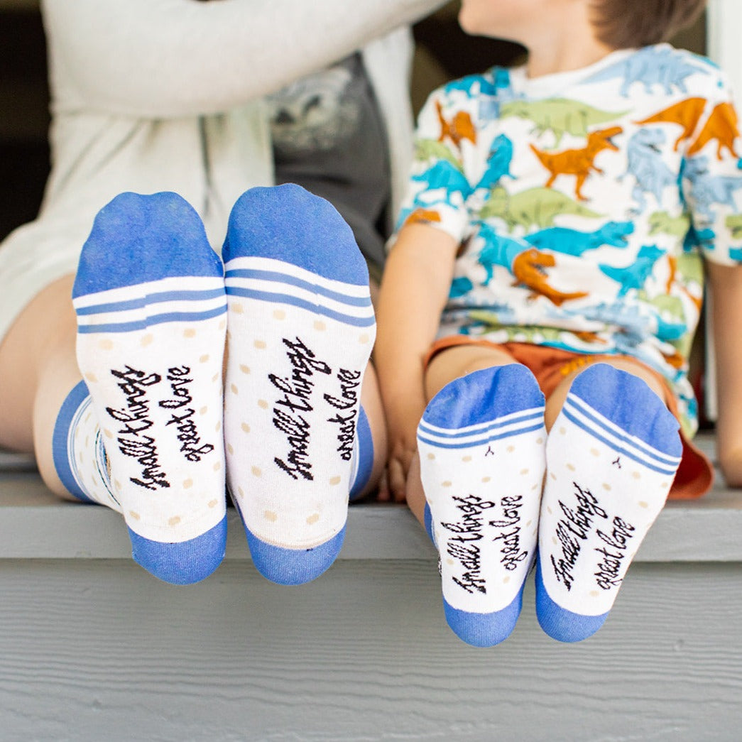 a young boy sitting on a bench next to a woman wearing a pair of blue and white socks with a picture of a man wearing a hat