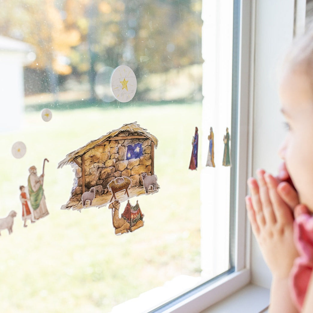 close up of little girls praying in front of the Nativity Cling set on a window