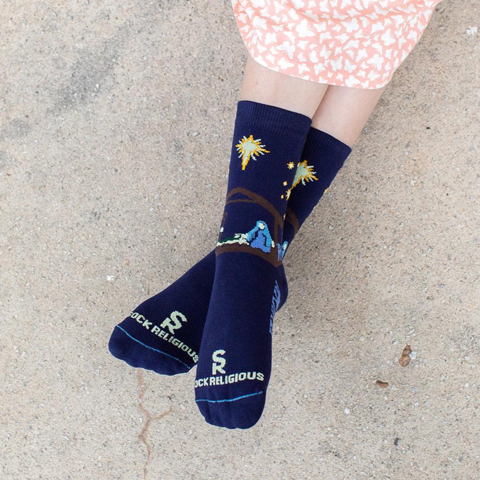 gilr wearing dark navy blue socks featuring simple silhouettes of the manger scene