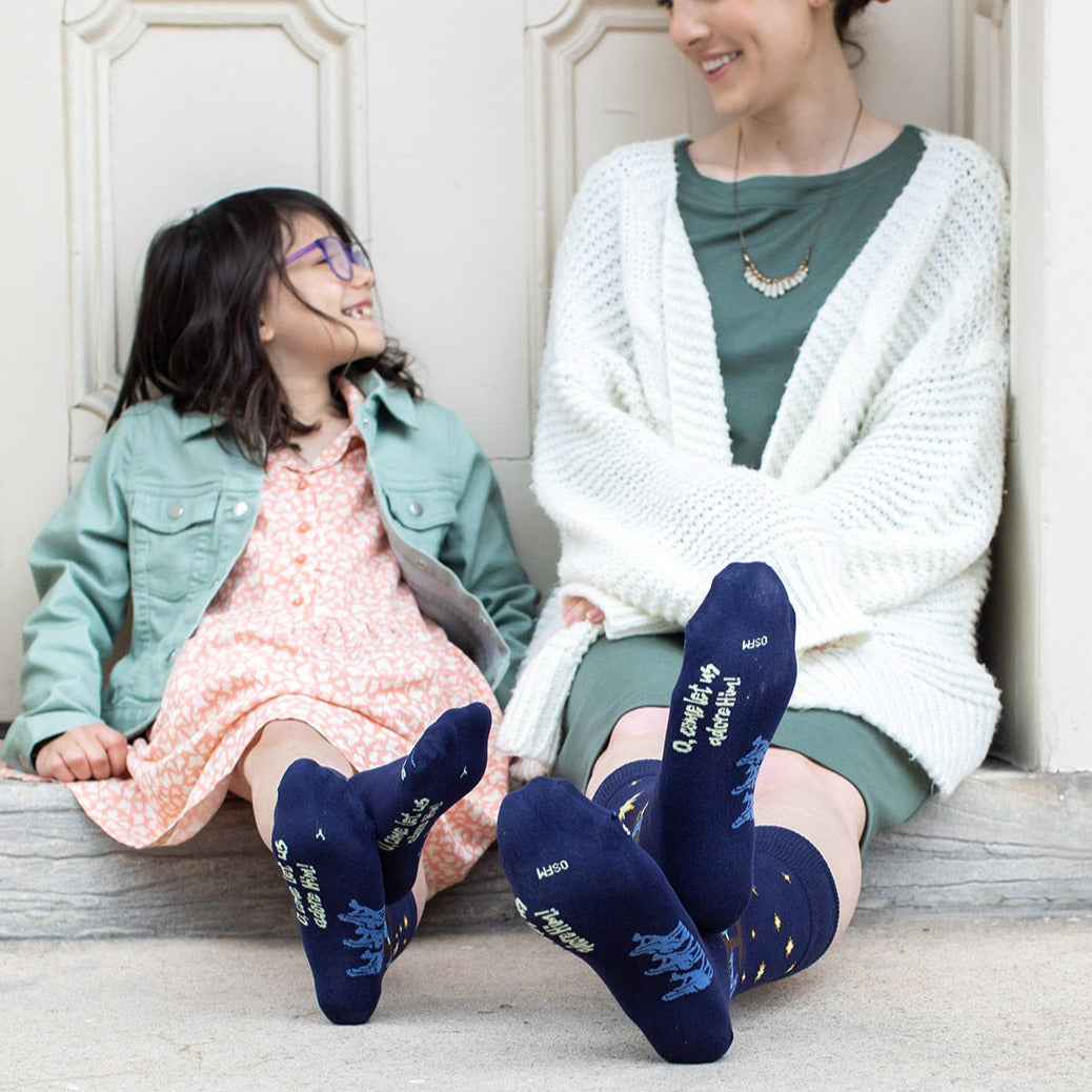 far away shot of girl and mom wearing dark navy blue socks featuring simple silhouettes of the manger scene