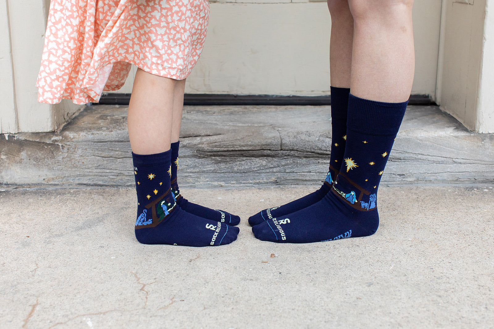 girl and mom facing each other wearing dark navy blue socks featuring simple silhouettes of the manger scene