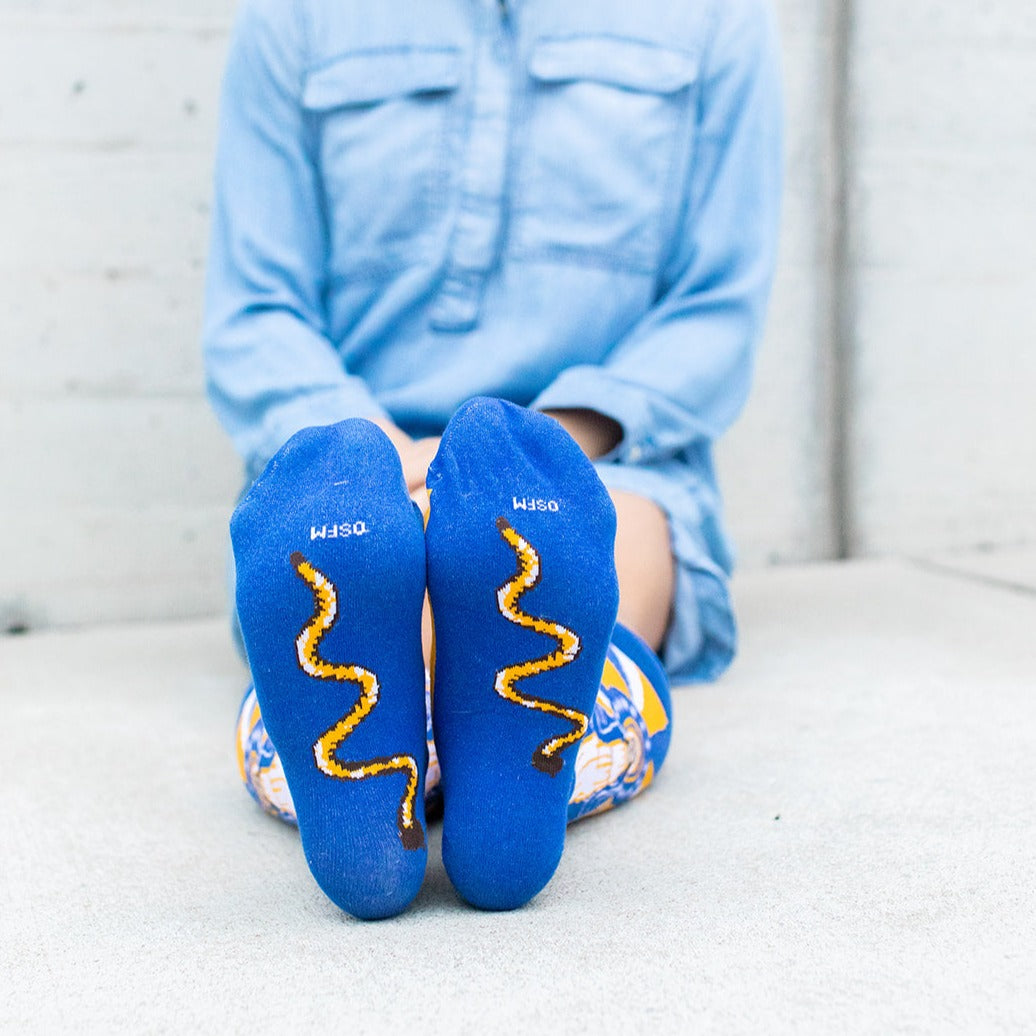 woman wearing Our Lady of Grace socks with Mary, yellow and blue rays, showing the serpant on the bottom of the foot