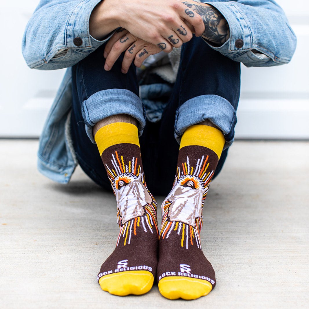 a person sitting on the ground wearing a pair of brown socks with a picture Jesus Christ
