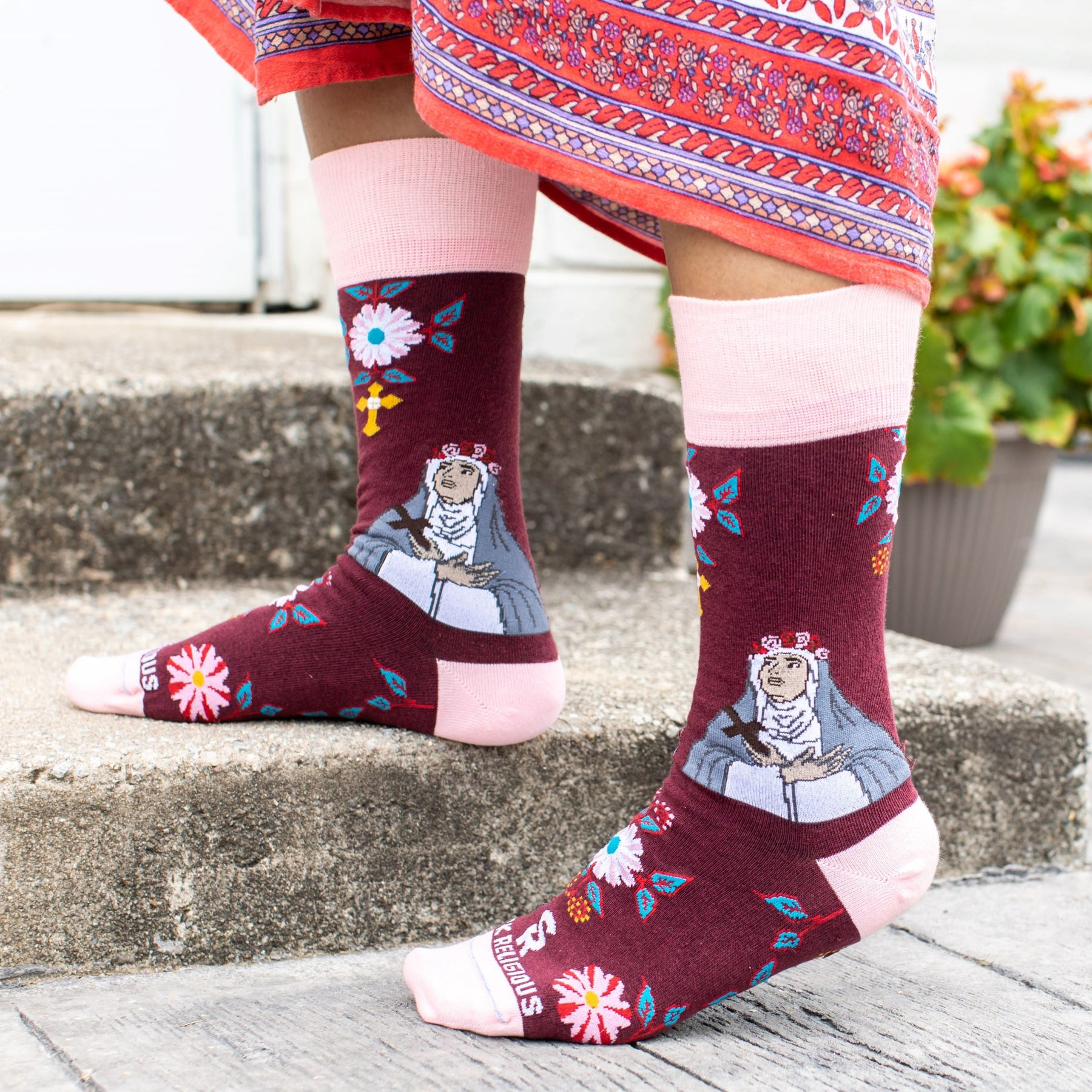 A person standing and steps wearing a pair of pink and red sock with a picture of St. Rose of Lima on it