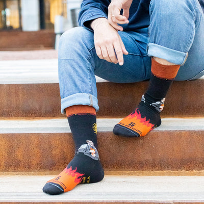 a man sitting on the steps with his feet up wearing a pair of socks with a picture of a man on it