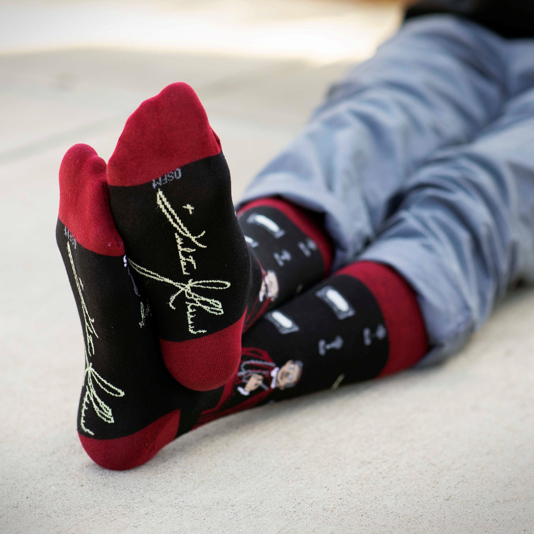 a person laying on the ground with their feet up wearing a pair of socks with a picture of a person on it