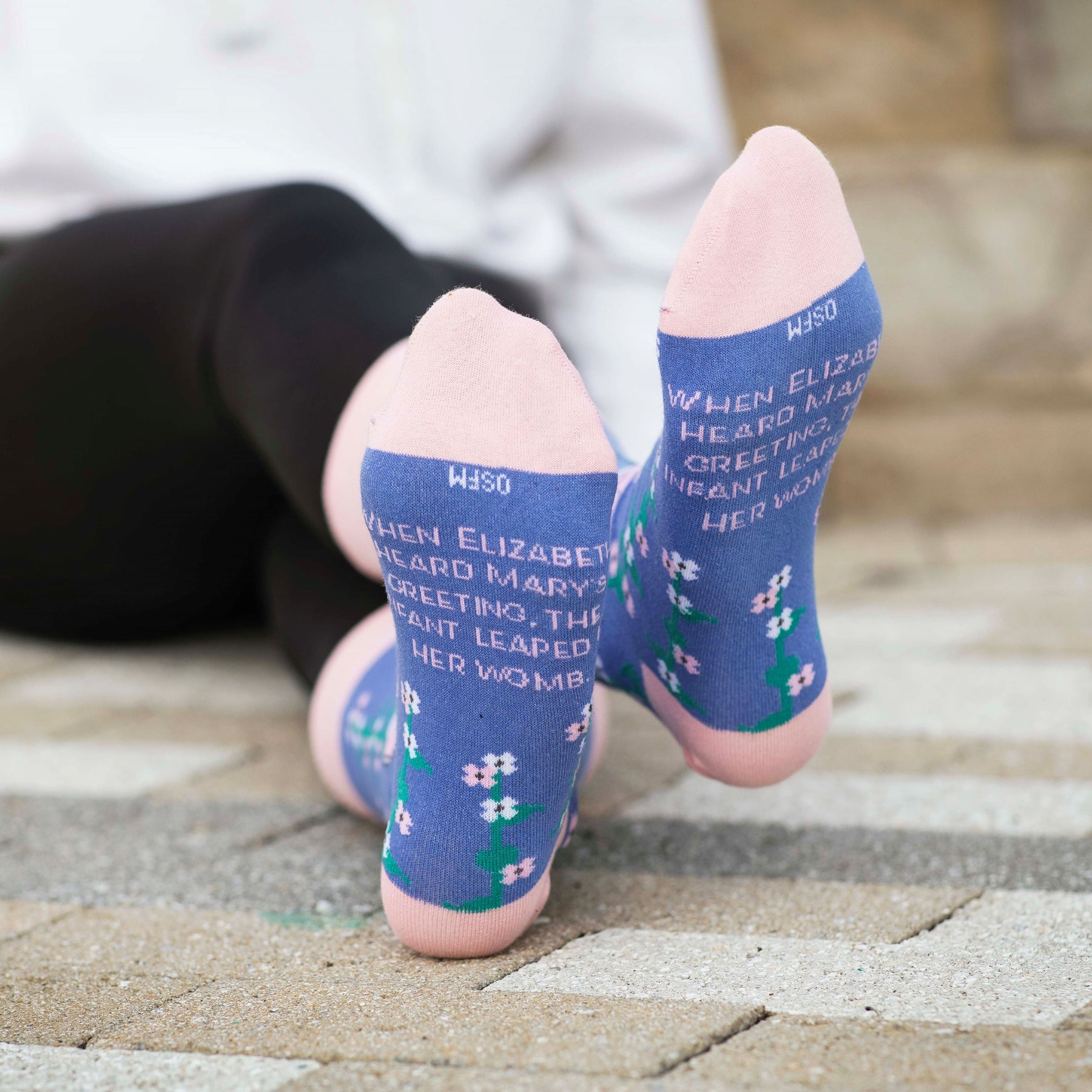a person laying on the ground with their feet up wearing a pair of socks with a picture of Mary and Elizabeth