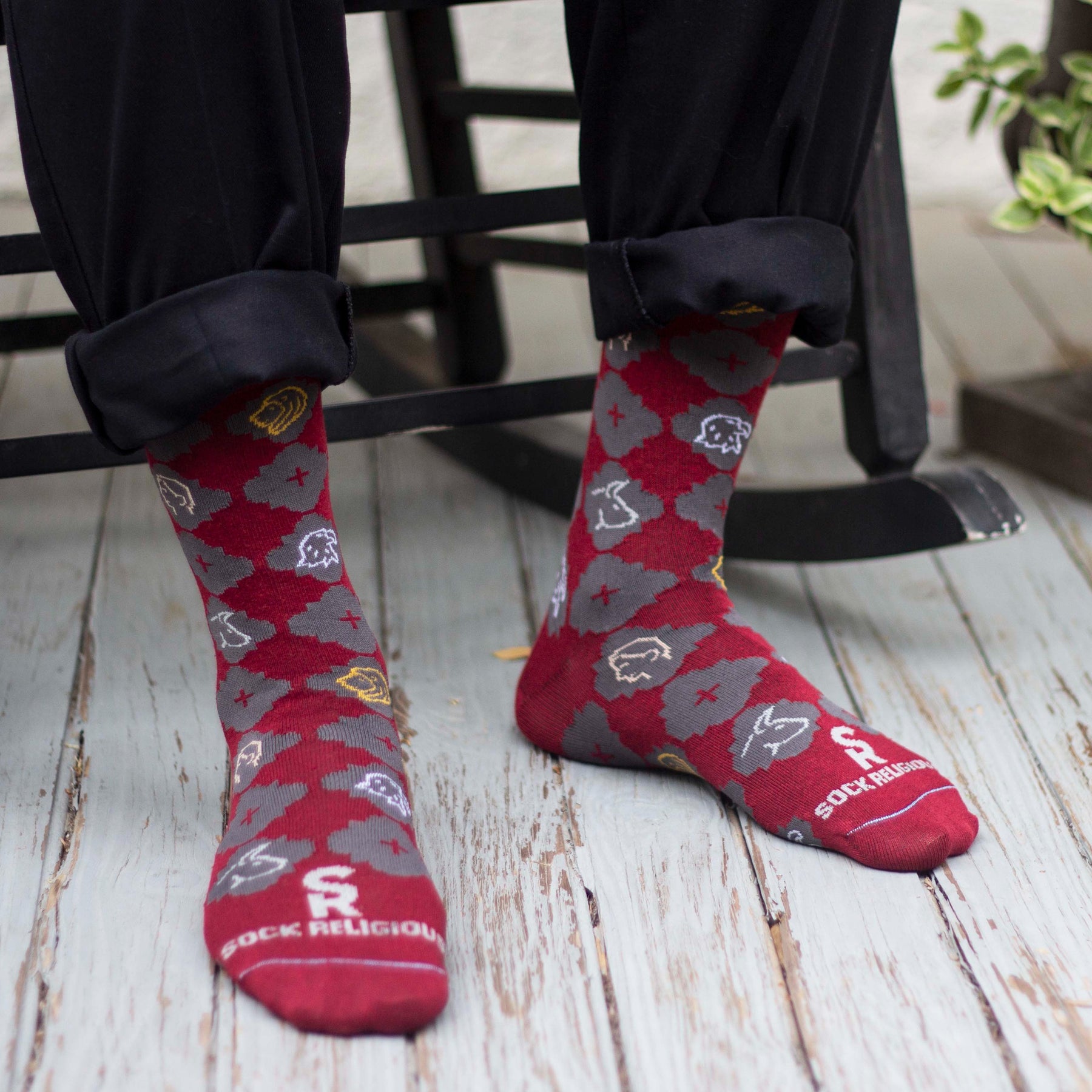 A persons sitting on a chair wearing a pair of red socks with a pattern design on it
