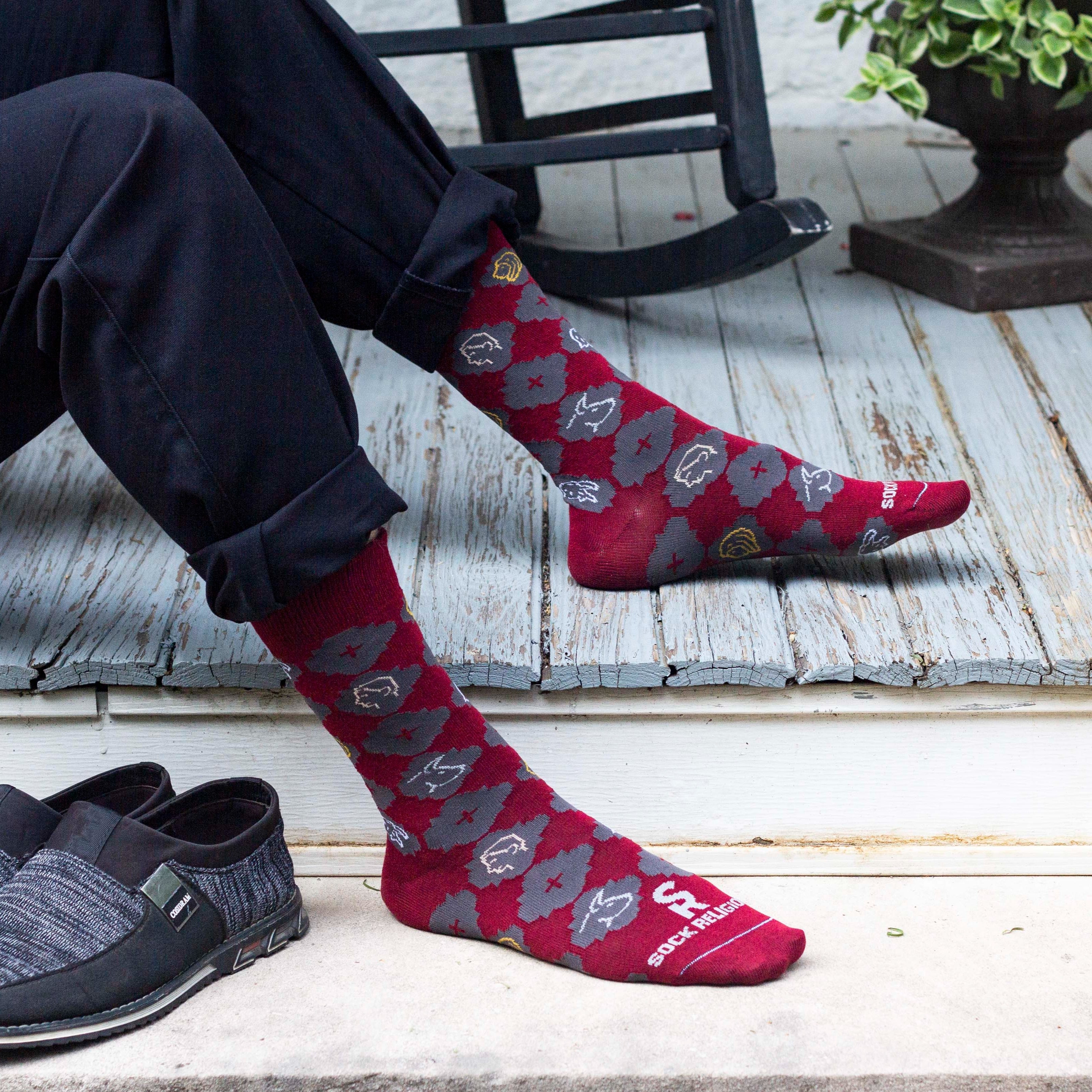 A persons sitting on the ground wearing a pair of red socks with a pattern design on it
