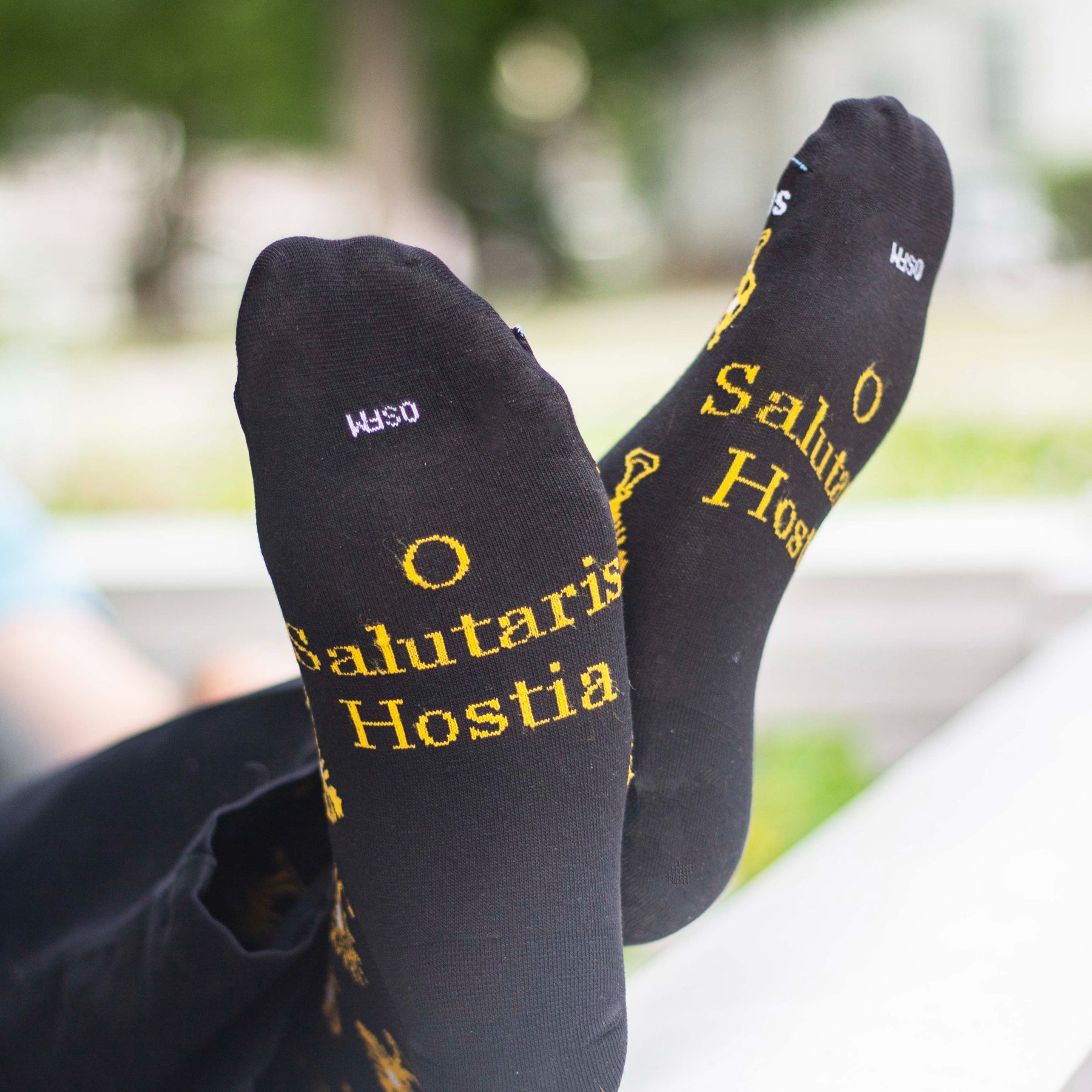 A close-up of feet in black socks with golden monstrances and text on it