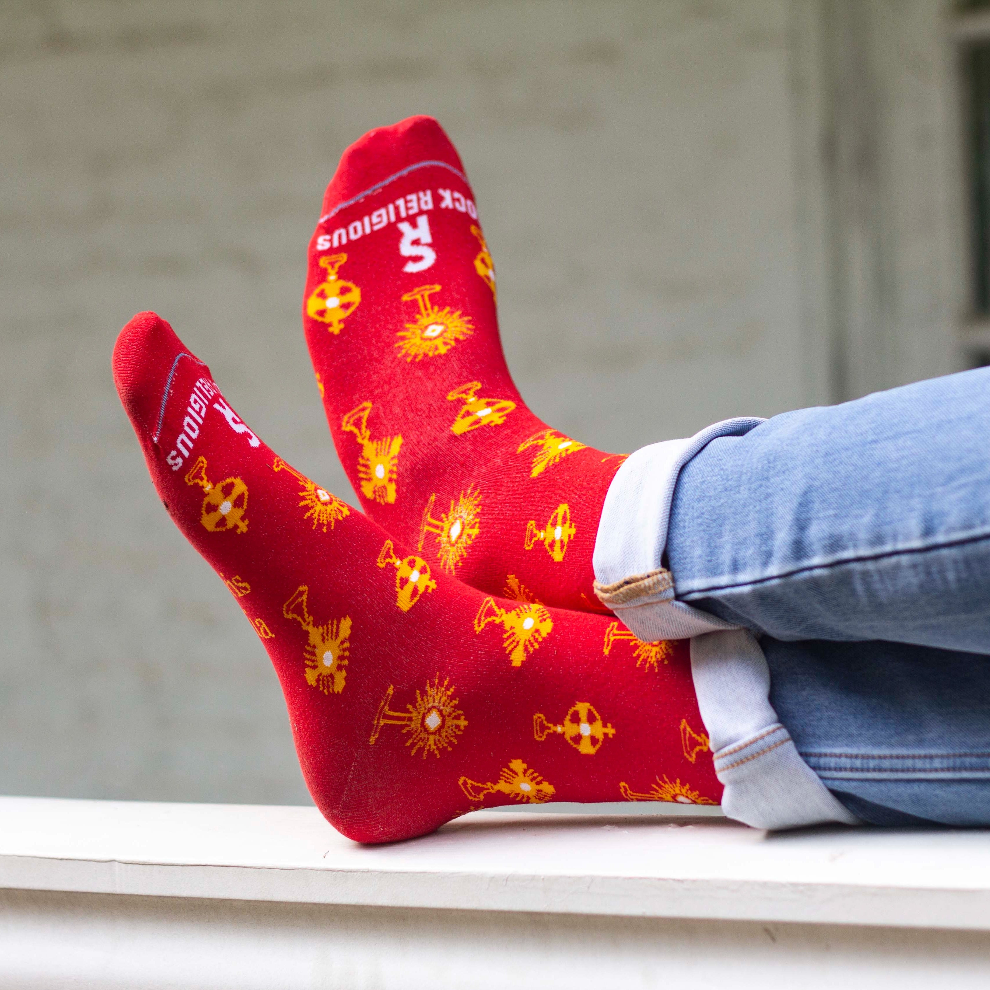 Feet in red socks with gold monstrances and text