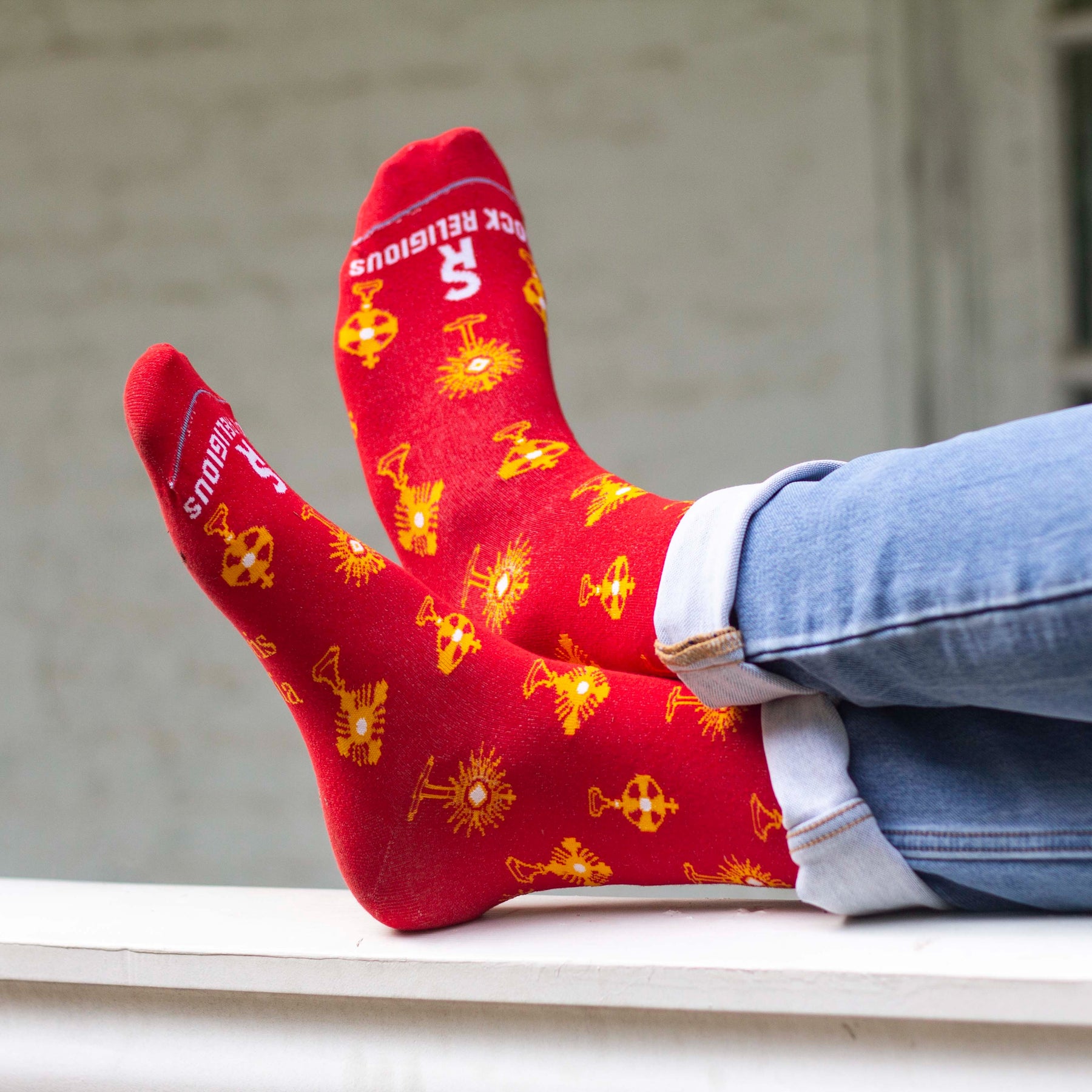 Feet in red socks with gold monstrances  and text