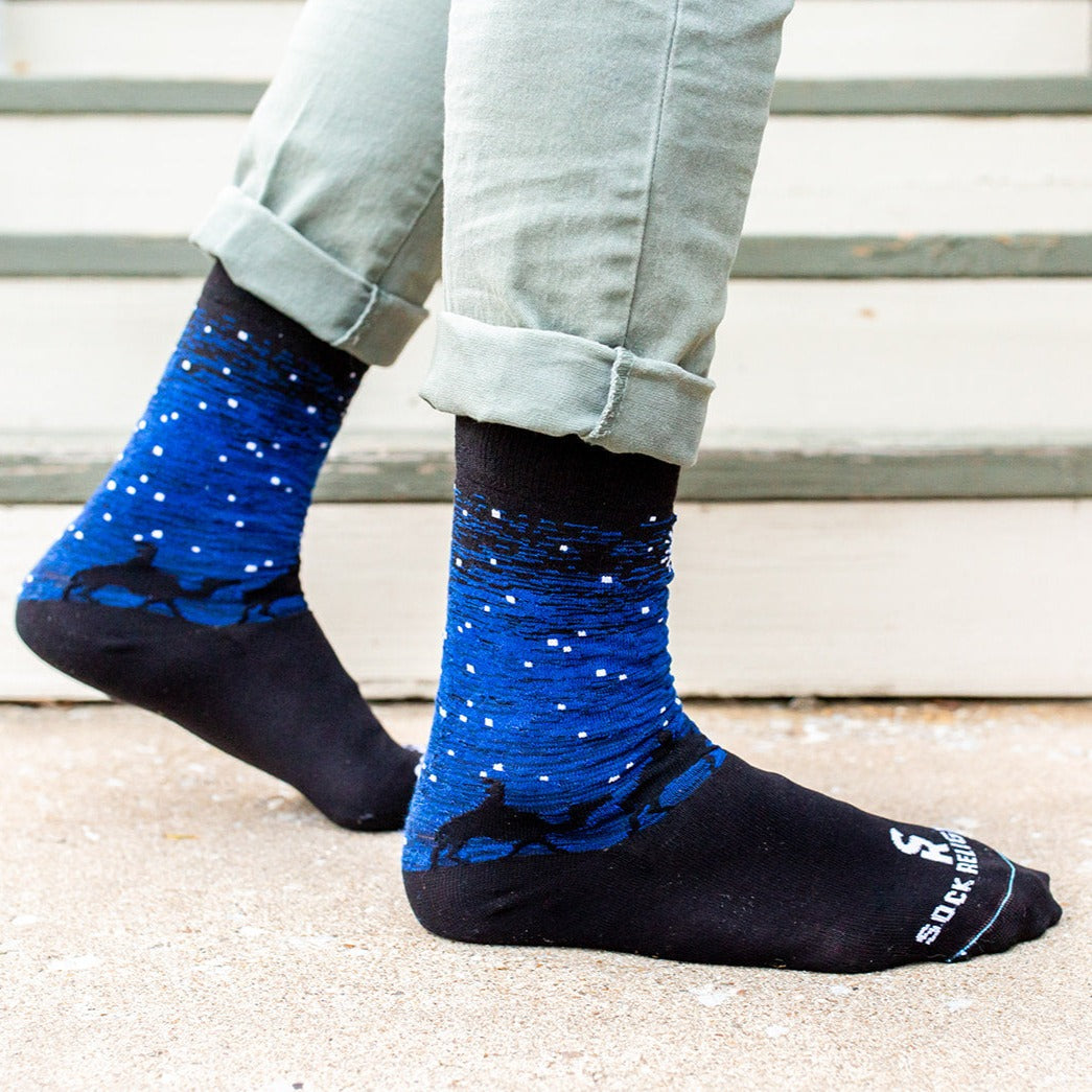 man standing wearing Black and blue socks featuring silhouettes of the 3 wisemen on camels following a bright white star of bethlehem, profile image