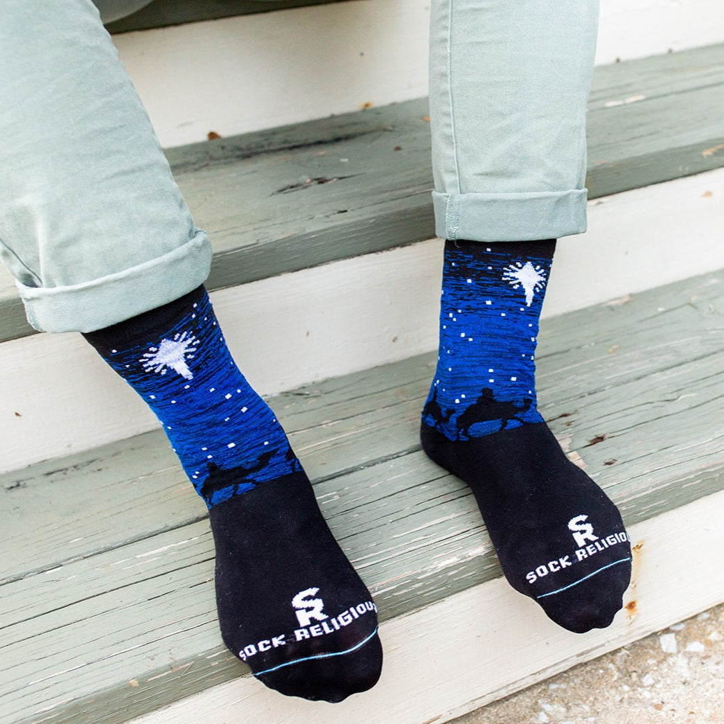 a person sitting on a step with their feet up wearing a pair of Three Wisemen socks