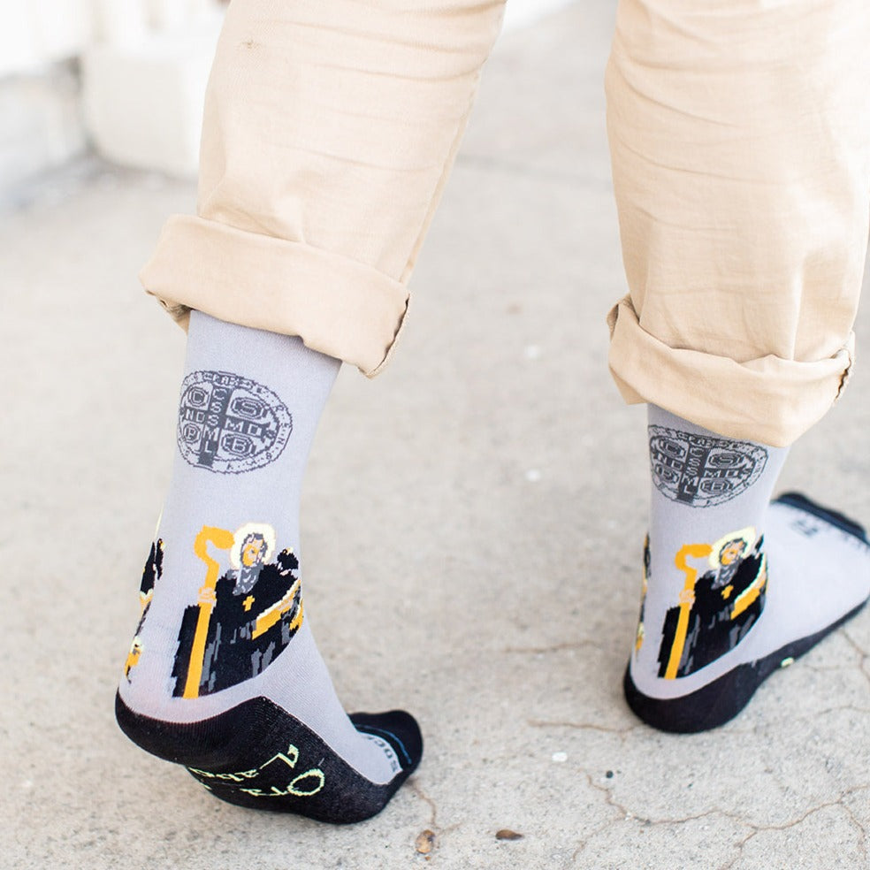 a person wearing a pair of socks with a picture of St. Benedict