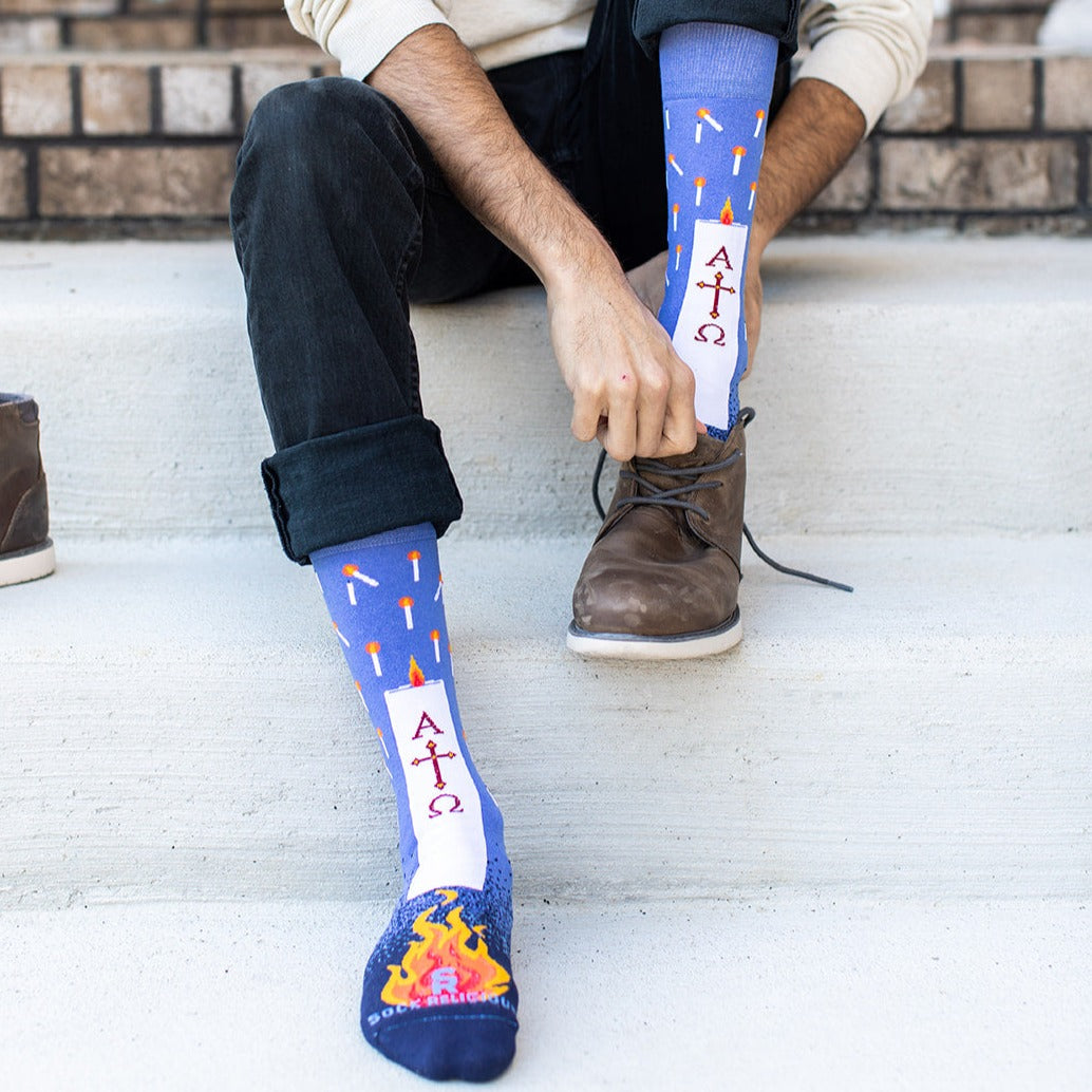 a man sitting on a step with a pair of blue socks with candles and shoes on them