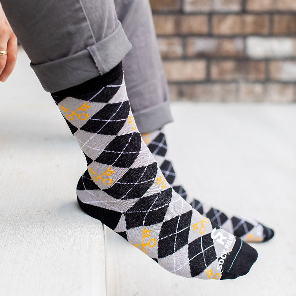 man wearing keys to the kingdom adult socks, argyle pattern in gray and black with yellow keys