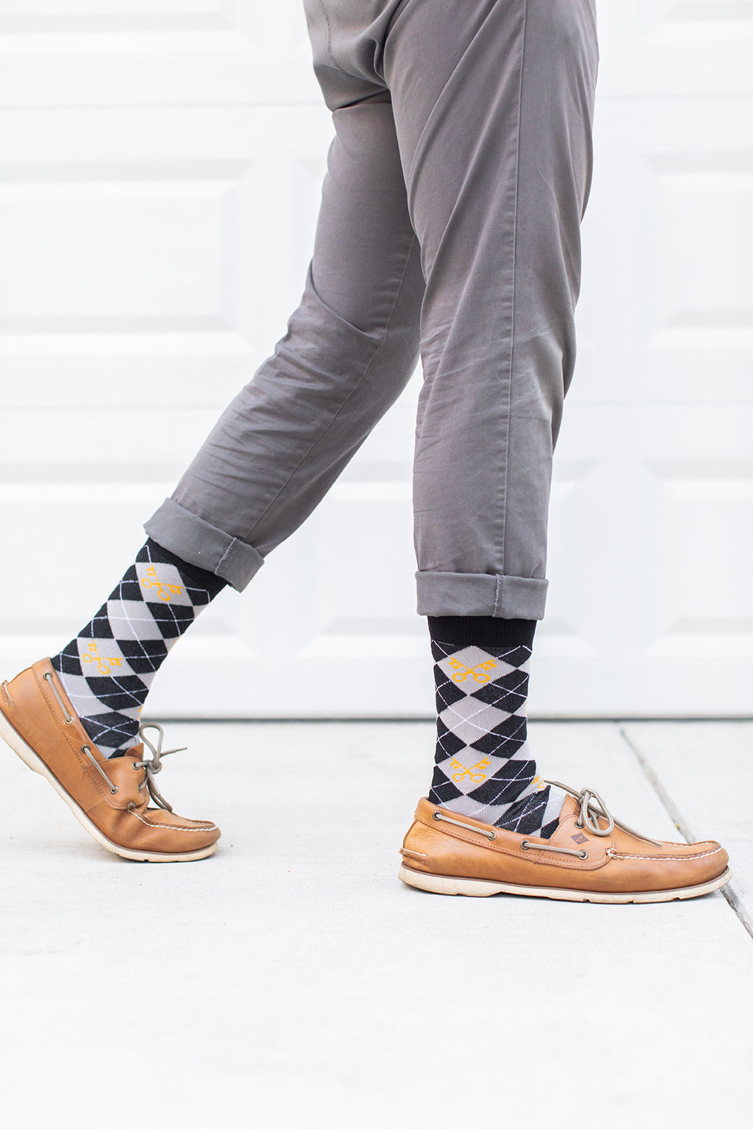 man wearing keys to the kingdom adult socks, argyle pattern in gray and black with yellow keys with brown loafers