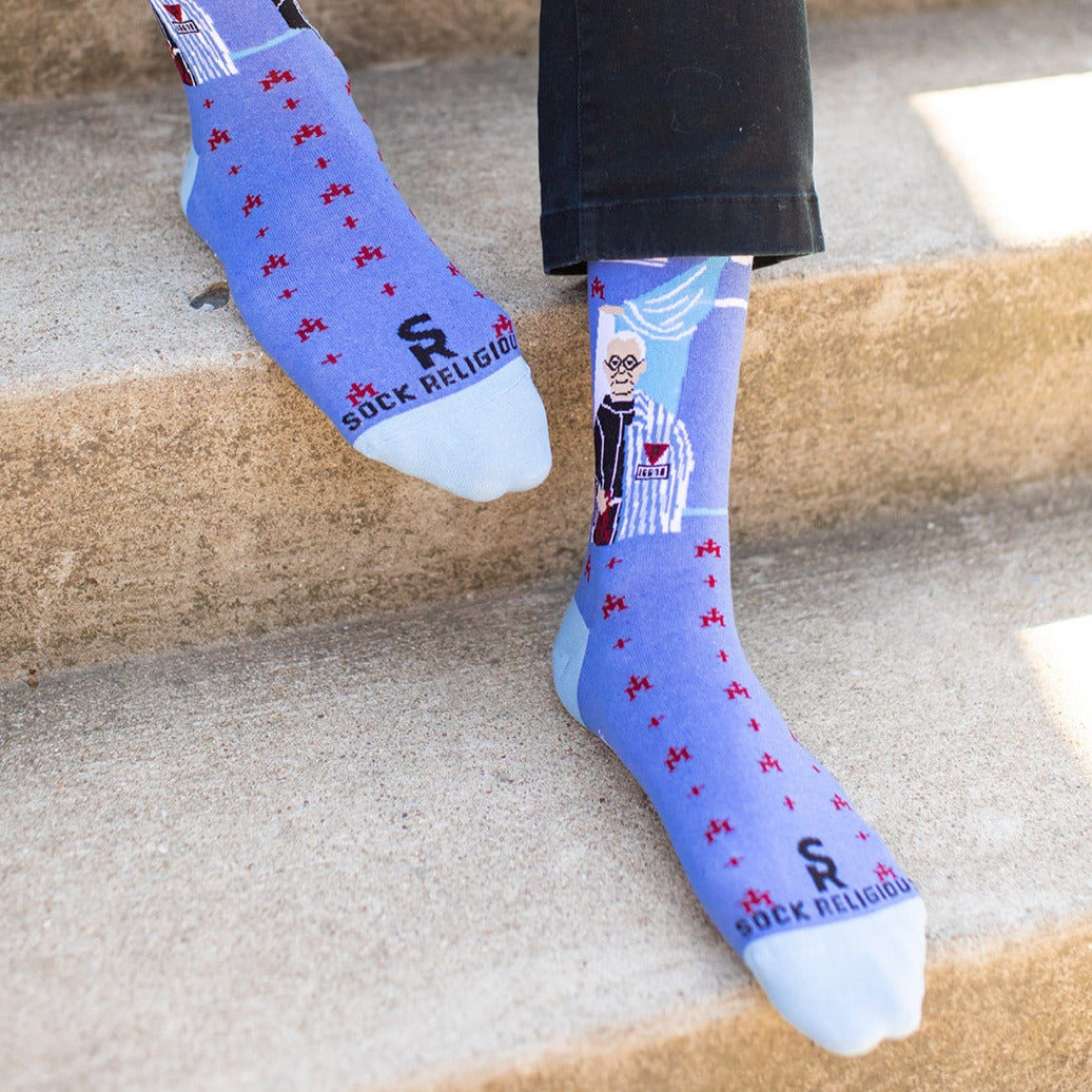 a person standing on a set of stairs wearing a pair of blue socks with a picture of St. Maximilian Kolbe