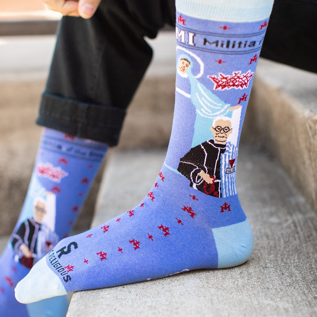 a person sitting on a ledge wearing a pair of blue socks with a picture of St. Maximilian Kolbe