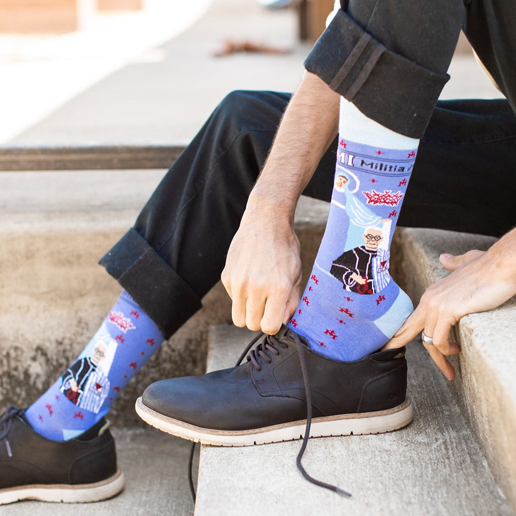 a person wearing a pair of black shoes with a pair of blue socks with a picture of St. Maximilian Kolbe