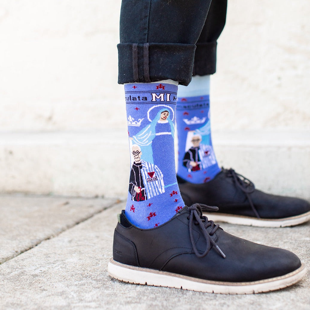 a person wearing a pair of black shoes with a pair of blue socks with a picture of St. Maximilian Kolbe