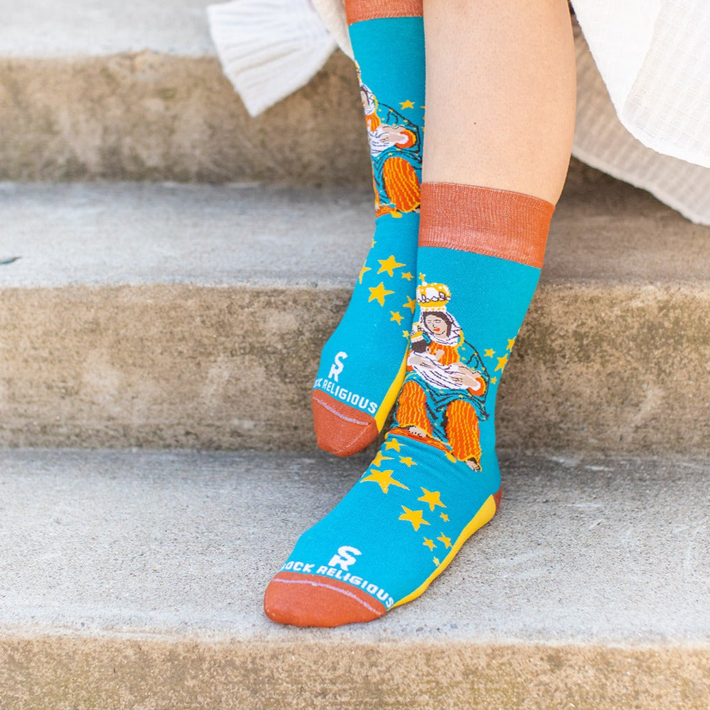 a woman sitting on the steps wearing a sock with a picture of Our Lady of La Leche