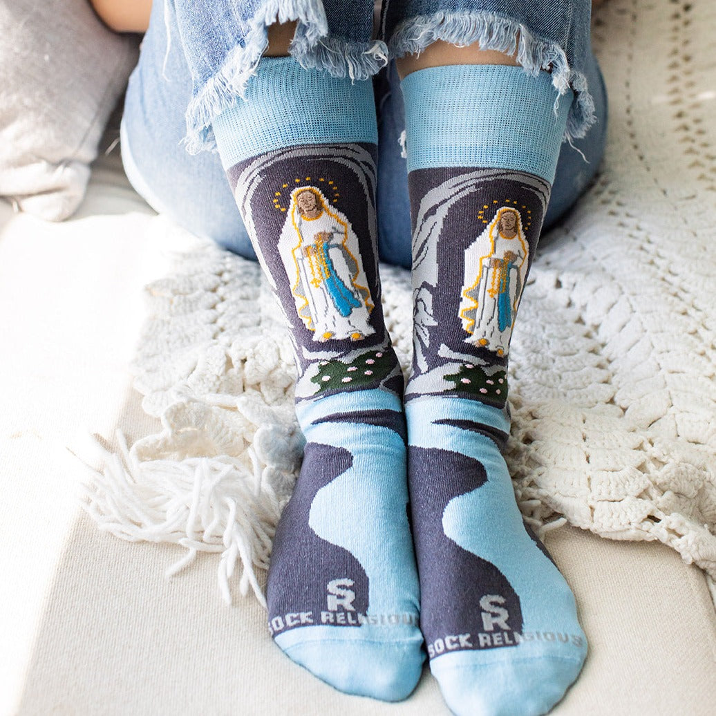 a person wearing a pair of socks with the image of Our Lady of Lourdes