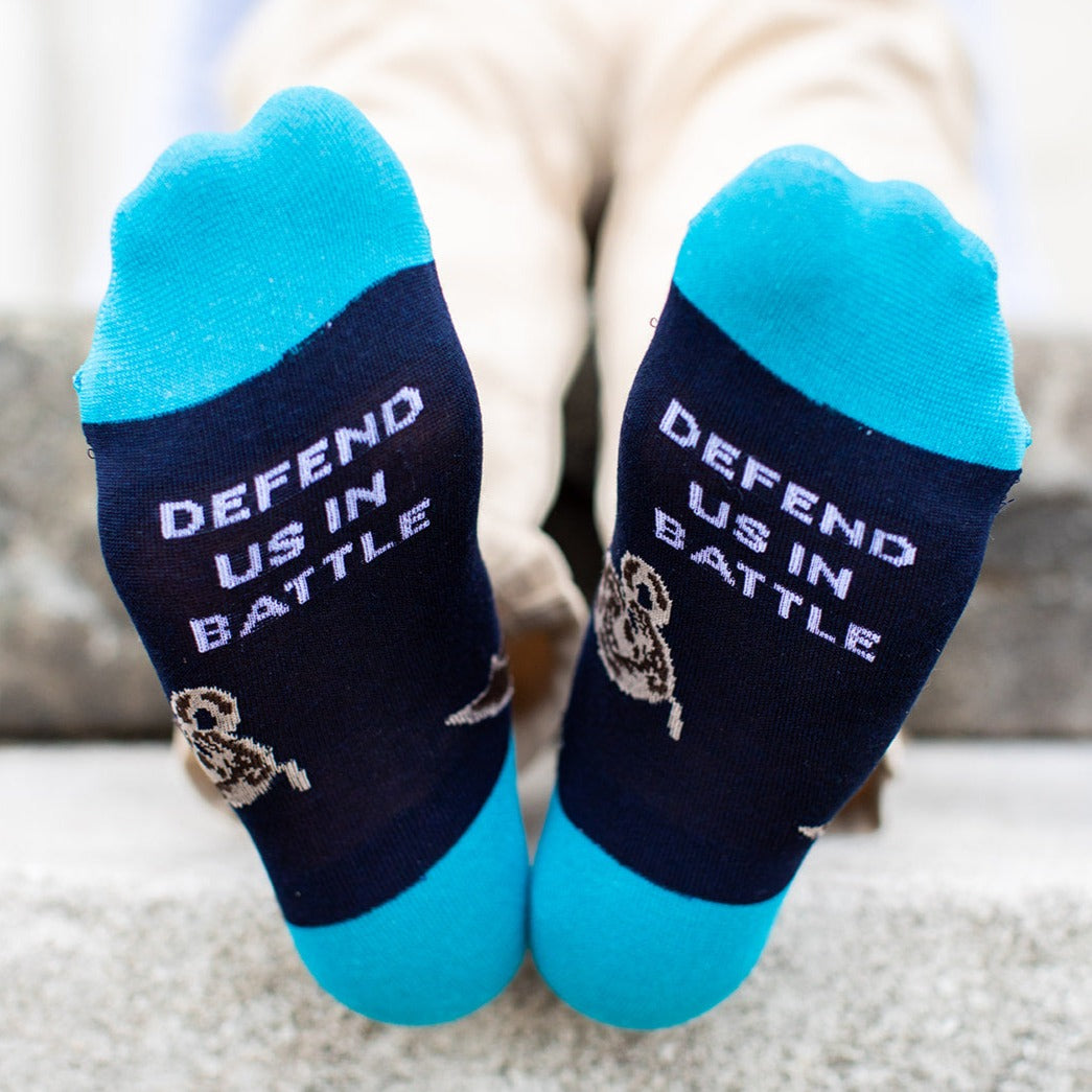 navy blue socks with St. Michael the Archangel slaying a demon and the words 'defend us in battle' on the bottom of the foot, this image shows the bottom of the foot