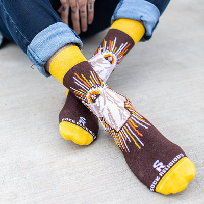 a person sitting on the ground with a pair of brown socks with a picture Jesus Christ