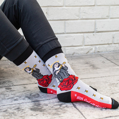 a person sitting on the ground wearing a pair of socks with a picture of St. Rita