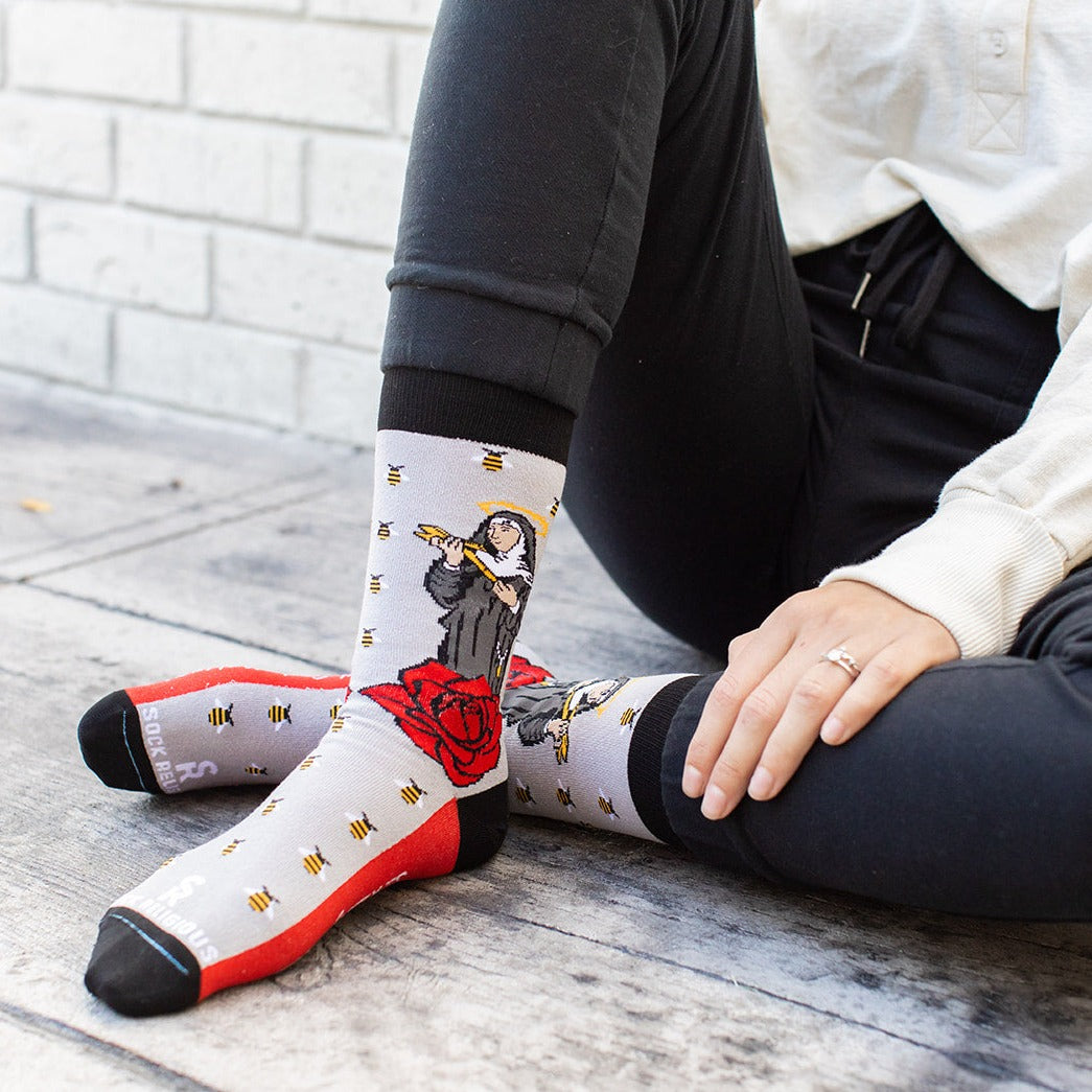 a person sitting on the ground wearing a pair of St. Rita socks