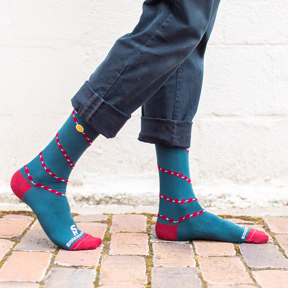 a person standing on a brick floor wearing a pair of socks with a design of rosary
