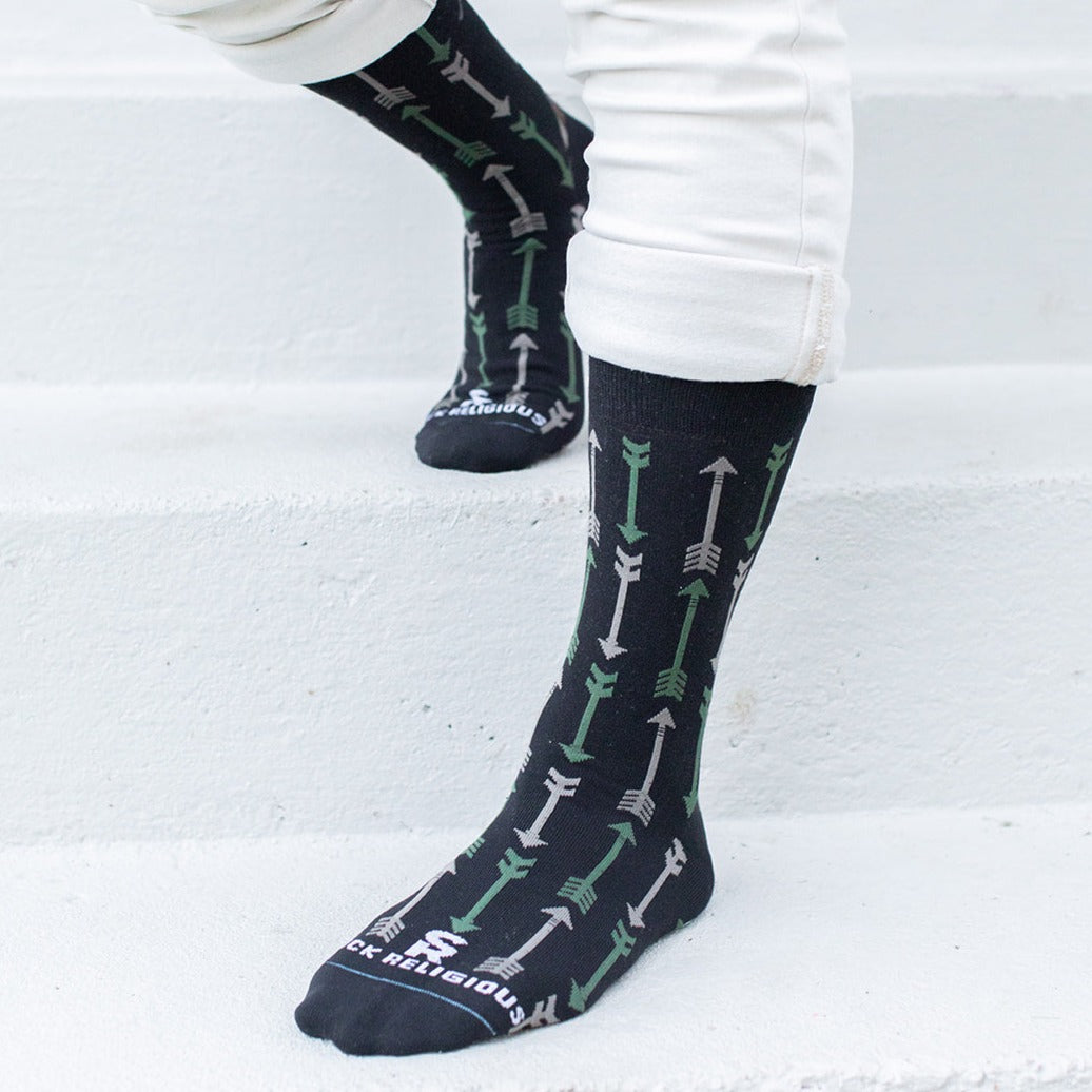 a person standing on a set of stairs wearing black socks with green arrows on them