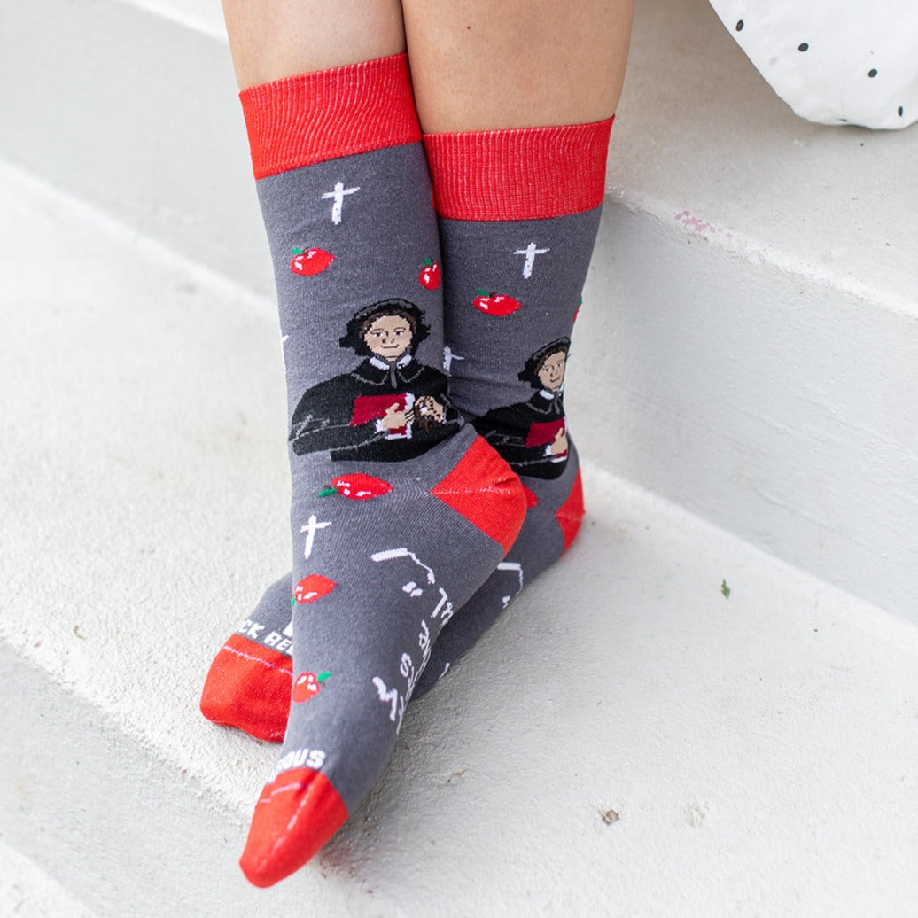 a person sitting on a step wearing a pair of socks with a picture of St. Elizabeth Ann Seton