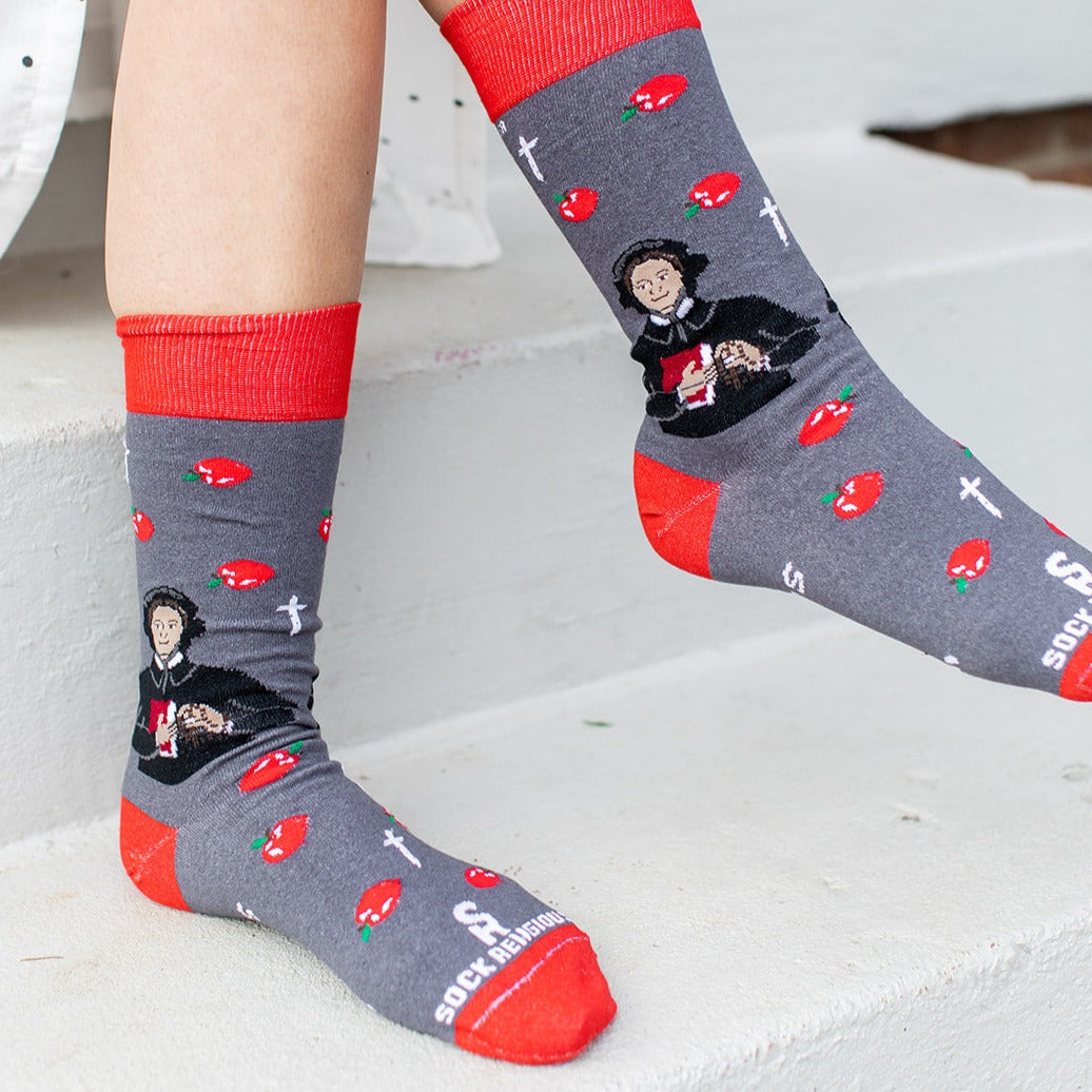 a person sitting on a step wearing a pair of socks with a picture of St. Elizabeth Ann Seton