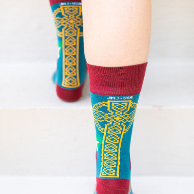 a close up of a person's legs wearing a pair of socks with a picture of St. Dymphna