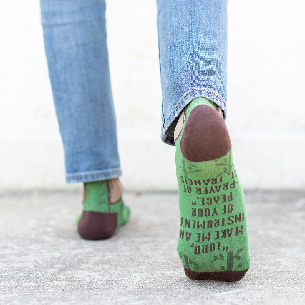 a walking showing the bottom of their St. Francis of Assisi socks, the bottom says "Lord, make me an instrument of your peace."