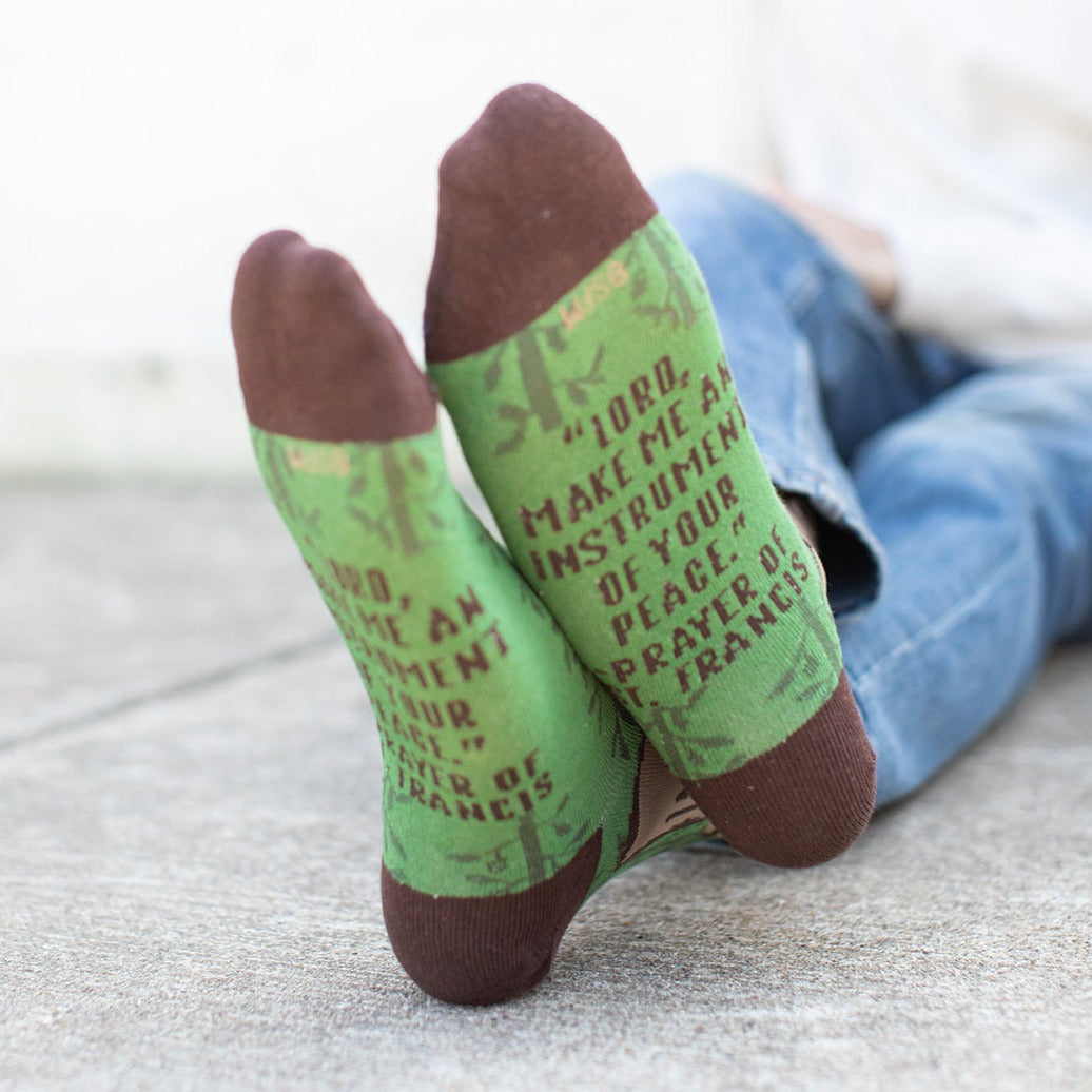 a person wearing St. Francis of Assisi socks, the bottom says "Lord, make me an instrument of your peace."