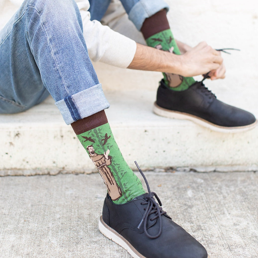 a man sitting on a step wearing St. Francis of assisi socks and black dress shoes
