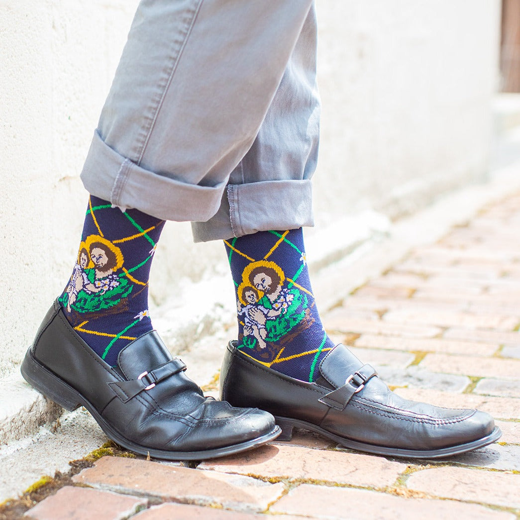 a person standing on brick wearing a pair of black dress shoes and St. Joseph socks