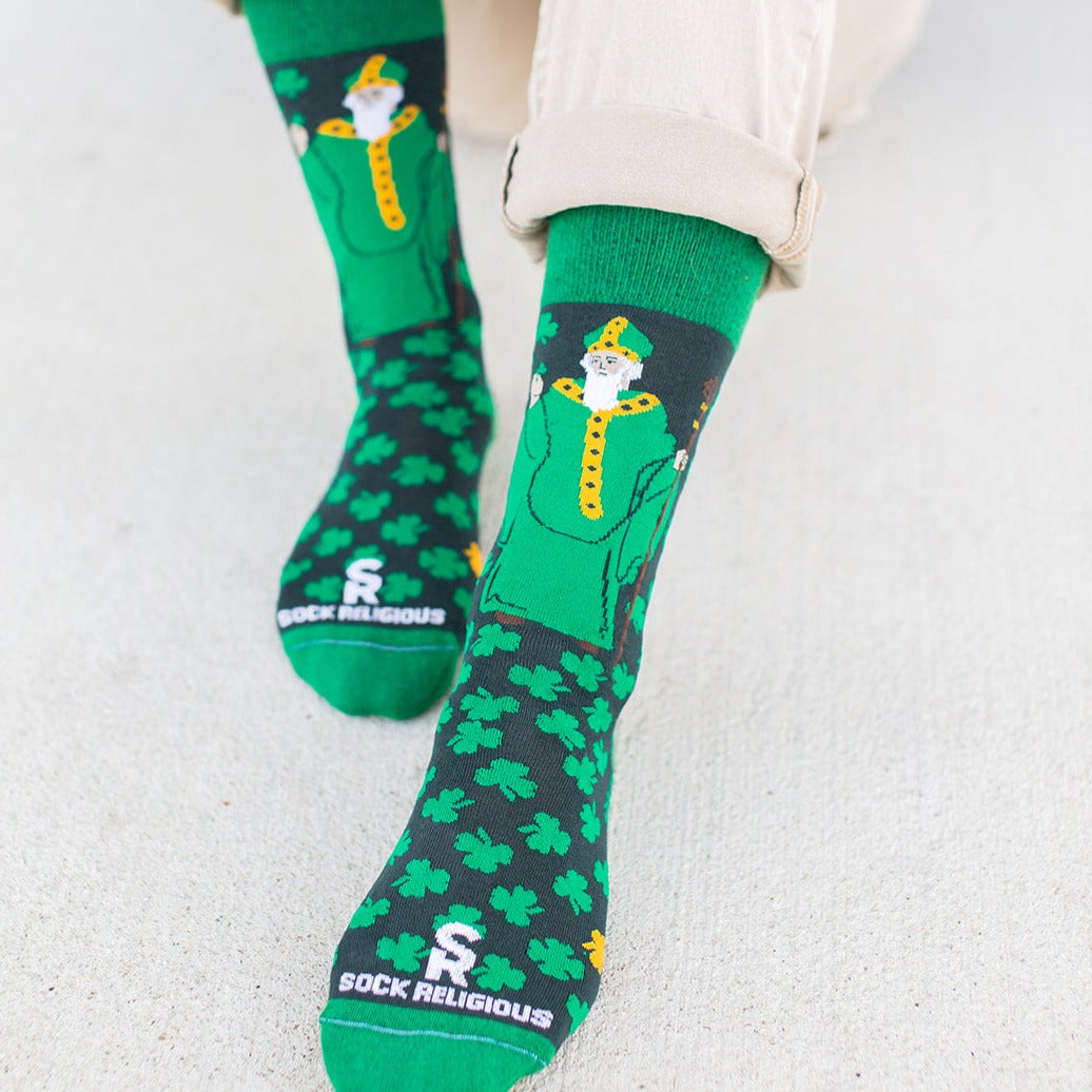 a person wearing green socks with shamrocks and St. Patrick on them
