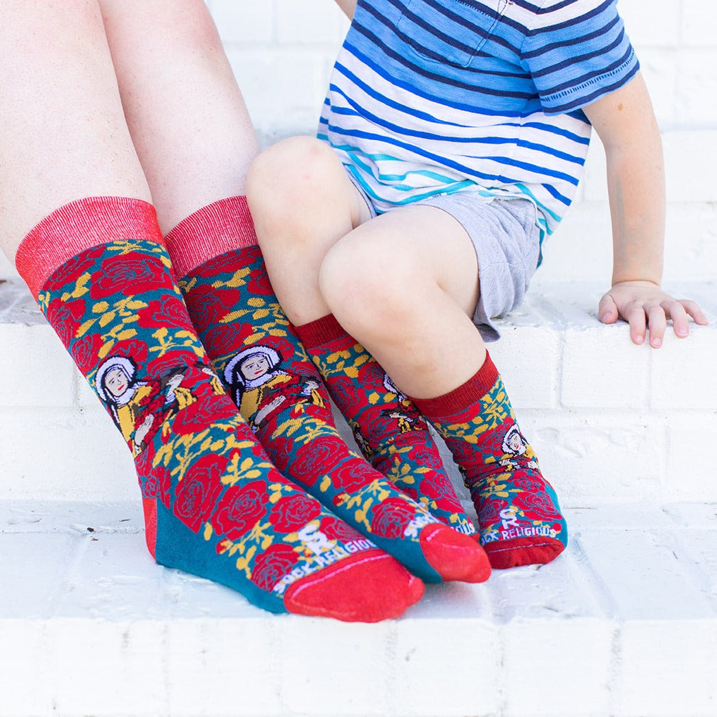 a little boy sitting on a ledge with his mom both wearing St. Therese of Lisiuex socks
