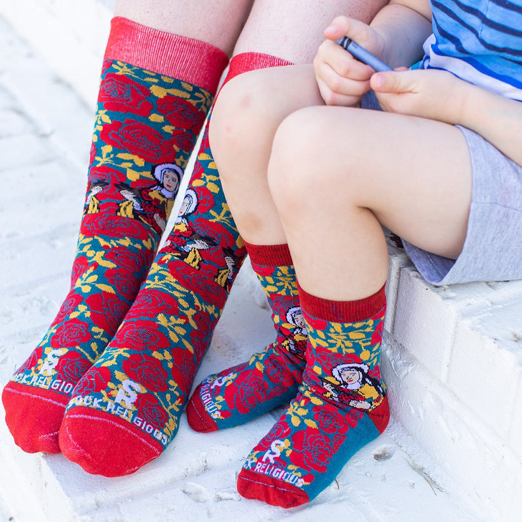 a little boy sitting on a step with his mom both wearing St. Therese of Lisiuex socks