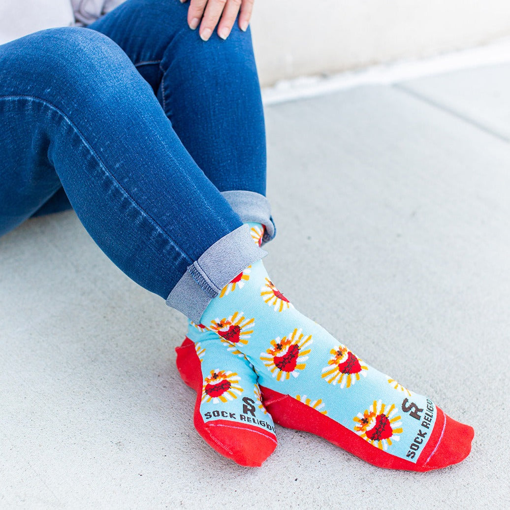 a woman sitting on the ground wearing a pair of red and blue Sacred Heart socks